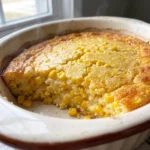 Creamed corn casserole with golden corn muffin crust, creamy sour cream base, and whole corn kernels throughout.